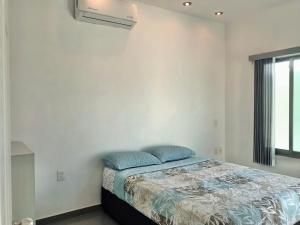 Dormitorio blanco con cama con almohadas azules en Casa de Colima en Colima