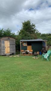 einen Hof mit einem Schuppen, einem Tisch und Stühlen in der Unterkunft Willowdene shepherds hut in Oswestry