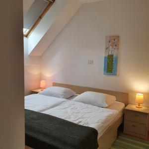 ein Schlafzimmer mit einem Bett mit weißer Bettwäsche und zwei Lampen in der Unterkunft Apartments Rombon in Bovec