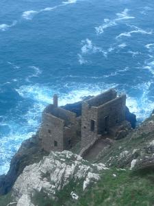 a building on top of a cliff next to the ocean at Dollys Den bell tent in St. Just