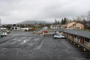 a parking lot with cars parked in front of a mountain at Scottish Inns Ashland in Ashland