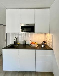 eine Küche mit weißen Schränken und einer Obstschale auf der Theke in der Unterkunft Menorca Chic Apartment Near Beach & Harbour in Cala'n Bosch + 24 Fotos