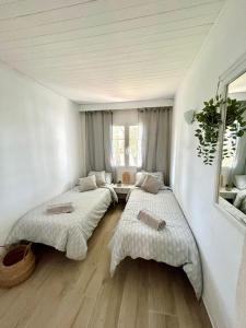 2 Betten in einem Zimmer mit weißen Wänden und Holzböden in der Unterkunft Menorca Chic Apartment Near Beach & Harbour in Cala'n Bosch