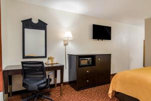マリエッタにあるQuality Inn Mariettaのベッド、デスク、椅子が備わるホテルルームです。