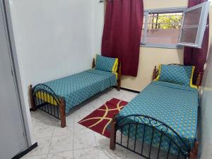 een kamer met 2 bedden en een raam bij Appartement Batha Hamria Meknes in Meknès