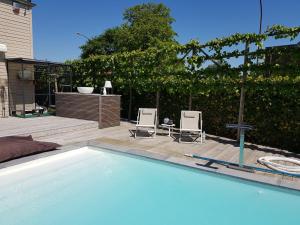 een zwembad met 2 stoelen en een patio bij Tomorrowland loft poolhouse with pool in Willebroek