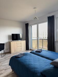 a bedroom with two beds and a large window at Apartament Nowa Cukrownia in Szczecin