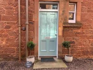 a blue door on a brick building with two plants at The Beach Pad North Berwick in North Berwick