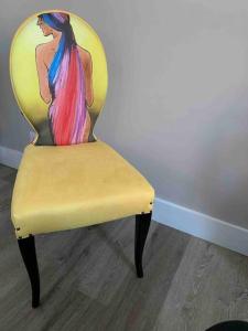 a yellow chair with a painting of a woman on it at The Beach Pad North Berwick in North Berwick