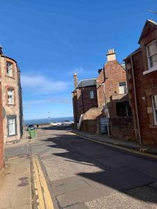 an empty street with brick buildings and the ocean at The Beach Pad North Berwick in North Berwick