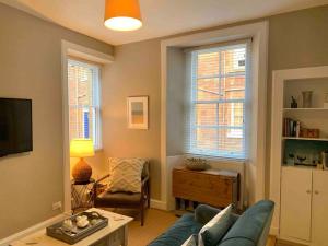 uma sala de estar com um sofá azul e duas janelas em The Beach Pad North Berwick em North Berwick