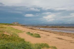 a sandy beach next to the ocean on a cloudy day at The Beach Pad North Berwick in North Berwick