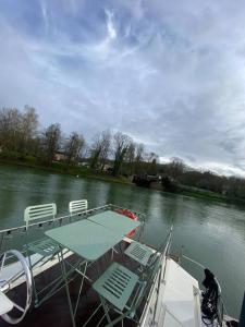 a boat with a table and chairs on the water at Charmant bateau sur la Marne in La Ferté-sous-Jouarre