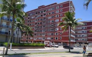un edificio rojo con palmeras delante en 92SOLDAPRAIA Apto preparado para vc e sua familia, en Praia Grande
