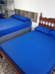 2 camas en una habitación con sábanas azules y almohadas azules en 92SOLDAPRAIA Apto preparado para vc e sua familia, en Praia Grande