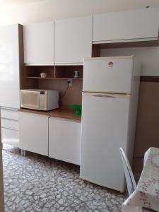 een keuken met een witte koelkast en een magnetron bij 92SOLDAPRAIA Apto preparado para vc e sua familia in Praia Grande