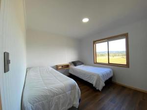 a small bedroom with two beds and a window at Cabaña Altos de Quento 2 , 8 personas equipada in Castro