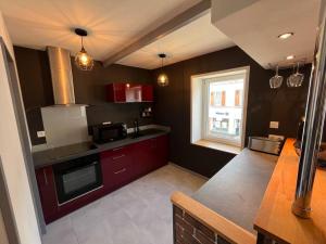 a large kitchen with red cabinets and a window at 36 avenue de la gare in Concarneau