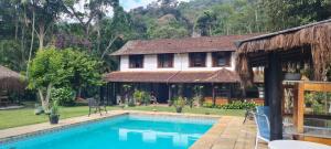 a house with a swimming pool in front of it at Kronemhouse Pousada in Petrópolis