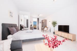 a white bedroom with a large bed and a tv at True Home in Sfakerá