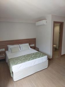 een slaapkamer met een groot wit bed in een kamer bij Flat Hotel Pedra Azul in Pedra Azul