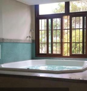 a large bath tub in a bathroom with a window at Flat Hotel Pedra Azul in Pedra Azul