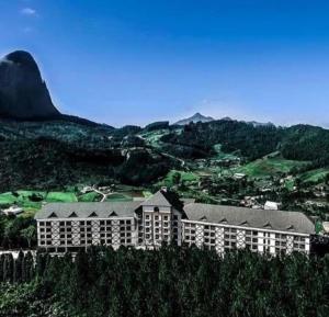 un grand bâtiment au sommet d'une colline avec des montagnes dans l'établissement Flat Hotel Pedra Azul, à Pedra Azul