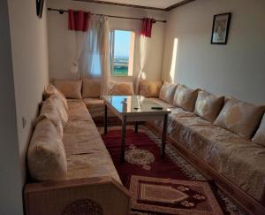 a living room with a large couch and a table at Havre de Paix chez Lamine in El Harhoura