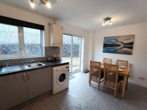 a kitchen with a sink and a table with a washing machine at Trevithick Gardens, No 47. in Merthyr Tydfil