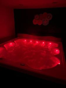 - un lit rouge avec des lumières rouges dans une chambre sombre dans l'établissement Roulotte la Bohême est son Spa en Baie de Somme, à Arrest