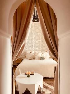 Riad Les Orangers D'alilia في مراكش: غرفة نوم بسرير وطاولة بيضاء