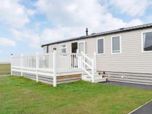 a mobile home with a white fence and grass at Seaview 1 in Heysham