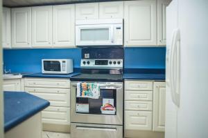 a kitchen with white cabinets and a stove and microwave at Seawind Beach Apartments in Montego Bay