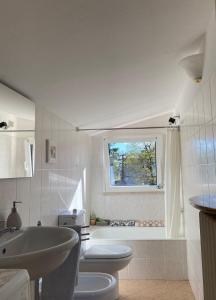 La salle de bains est pourvue d'un lavabo, de toilettes et d'une fenêtre. dans l'établissement Lakes&Hills Apartments, à Erba