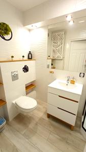 a white bathroom with a toilet and a sink at Meva Sopot Apartment in Sopot