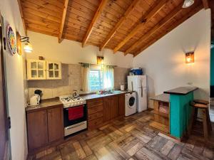 cocina con armarios de madera y nevera blanca en Hermosa casa vacacional a orillas del río en Potrero de los Funes