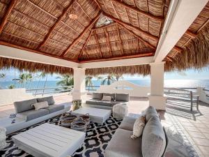 an outdoor living room with couches and a thatched roof at Villa Cobojo in Bucerías