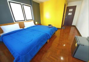 Cette chambre comprend un grand lit bleu et une télévision. dans l'établissement Doodle Lodge Chiang Mai, à Chiang Mai