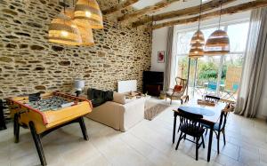 a living room with a ping pong table and a brick wall at LA VALLÉE DU LAUNAY GiTES in Taden