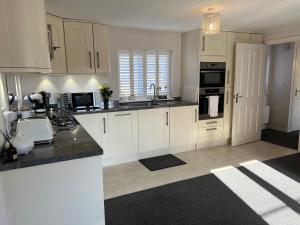 uma cozinha com armários brancos e um balcão preto em Cathedral Coach House em Lichfield
