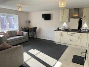 a living room with a couch and a kitchen at Cathedral Coach House in Lichfield