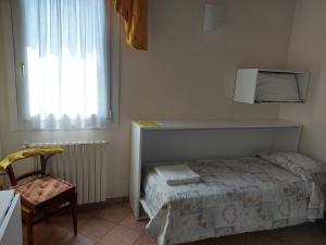 a bedroom with a bed and a chair and a window at Agriturismo Alla Casella in Ferrara