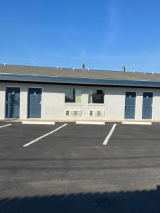 um edifício branco com portas azuis e um parque de estacionamento em Broadway Inn Motel em San Antonio