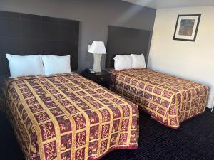 Una habitación de hotel con dos camas y una lámpara. en Broadway Inn Motel, en San Antonio 3 fotos más
