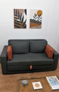 un divano nero in soggiorno con dipinti alle pareti di Apezinho.Loft 3 (Retrô) a Rio de Janeiro