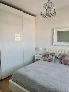 ein weißes Schlafzimmer mit einem Bett und einem Kronleuchter in der Unterkunft Appartamento incantevole a Misano Adriatico in Misano Adriatico
