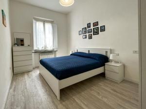 a white bedroom with a blue bed and a window at Villino La Fresia in Castiglioncello