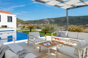 eine Terrasse mit weißen Möbeln und Poolblick in der Unterkunft Luxury Villa Dolac by Trogir and Split, complete privacy in untouched nature with infinity massage heated pool in Marina