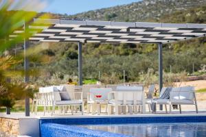 eine Terrasse mit weißen Stühlen und einem Pool in der Unterkunft Luxury Villa Dolac by Trogir and Split, complete privacy in untouched nature with infinity massage heated pool in Marina