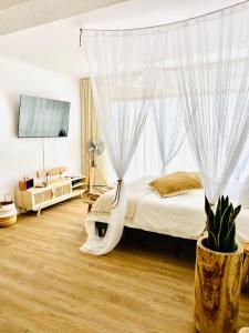 een slaapkamer met een bed met witte gordijnen bij Caparica Rooftop Beach Apartment in Costa da Caparica